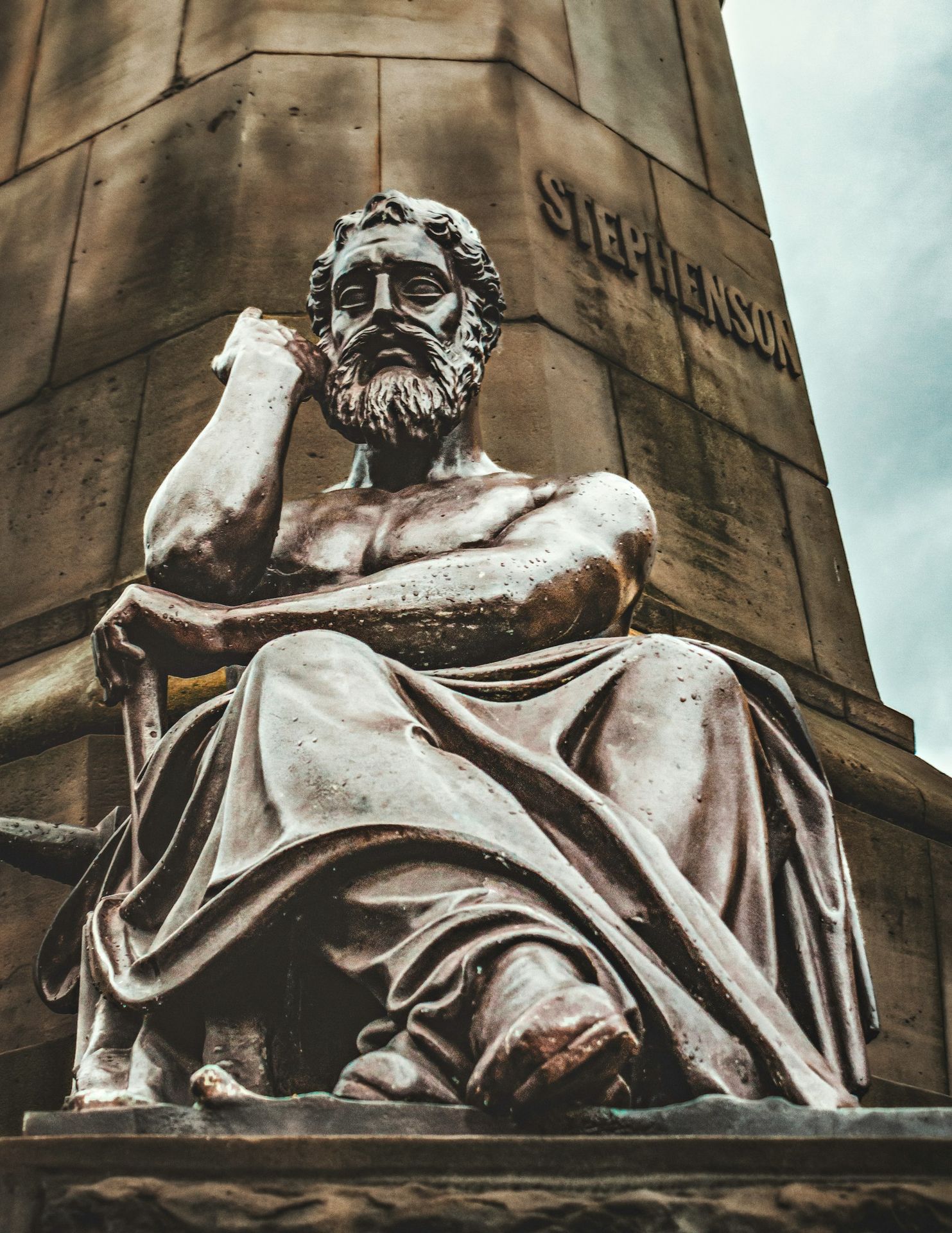 a statue of a man sitting next to a tall tower